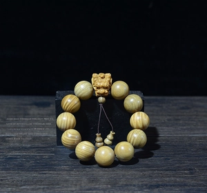 Gros plan de perles en bois de santal avec breloque Pixiu et petits pendentifs gourde