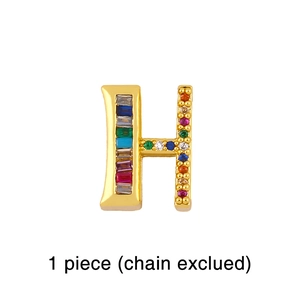Detailed macro of gold H-shaped letter pendant with colorful gemstones and rectangle cut