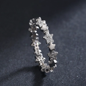 Eternity ring with polished silver stars and pavé diamond-like stones on a black surface