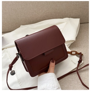 Detail view of burgundy leather flap bag with decorative amber resin chain strap