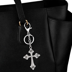 Silver cross keychain with crystals on a black leather bag showing lobster clasp design
