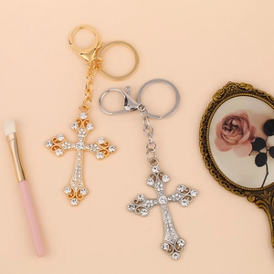 Elegant gold and silver cross keychains with rhinestones on a warm background