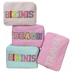 Close-up of four nylon makeup bags with colorful glitter and pearl letter patches