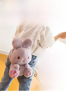 Detail of cute purple plush bunny bag with white braided strap worn by a young child