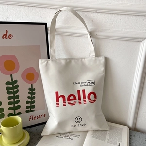 Detailed view of white canvas tote bag with red Hello print and smile face design