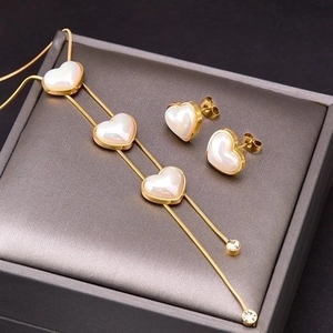 Golden stainless steel jewelry set with white heart pendants and earrings in a grey box