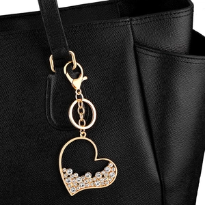 Gold heart keychain with sparkling crystals on black leather bag for women