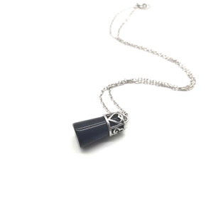 Close-up of black cylindrical pendant with silver hollow heart pattern on fine chain
