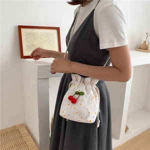 Side view of canvas bucket bag with cherry pattern and drawstring on model