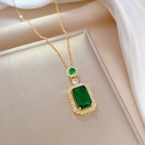 Titanium steel jewelry set with emerald pendant and matching earrings on silk background