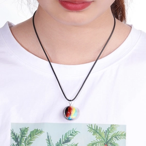 Detail of a handmade double-sided nebula glass ball pendant on a black leather cord