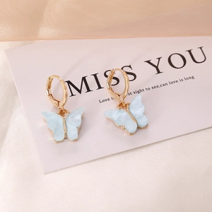 Blue marble butterfly earrings with gold hoops on white card and silk background