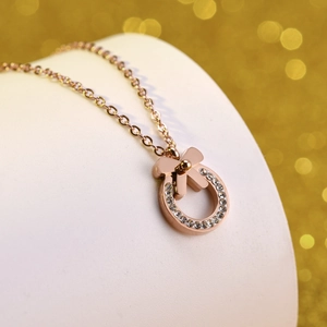 Macro shot of rose gold necklace with a sparkling pavé bow and circular pendant
