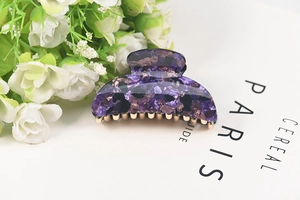 Detailed close-up of a purple tortoiseshell acrylic hair claw clip with a strong metal spring