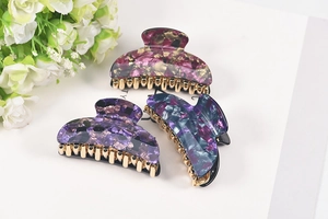 Detailed view of three acrylic floral hair claws in purple shell patterns with gold clips