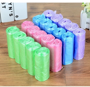Rolls of colorful disposable garbage bags in pink blue green and purple on wood