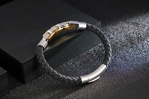 Detailed view of black woven leather bracelet with gold and silver stainless steel clasp