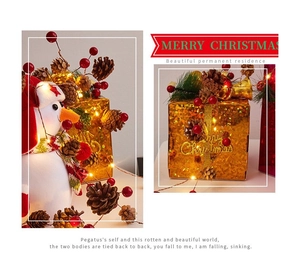 Detail of LED warm light string wrapped on Christmas pine cones and golden gift boxes