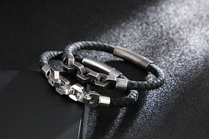 Macro detail of men's woven black leather bracelet with silver steel chain links