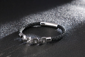 Detail of black woven leather bracelet with silver chain links and magnetic buckle