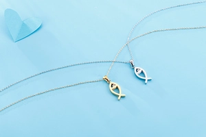 Detail of gold and silver fish-shaped necklaces with small gems on a blue background