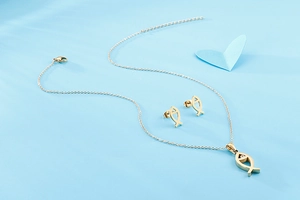 Detail of golden fish-shaped necklace and earrings set with sparkling white rhinestones