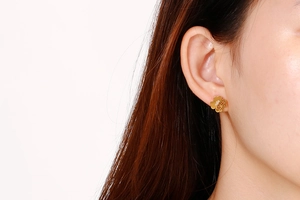 Detailed view of elegant gold hollow clover stud earrings on a female model