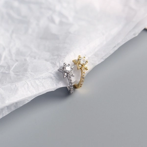 Macro detail of star-shaped earrings in gold and silver with sparkling cubic zirconia