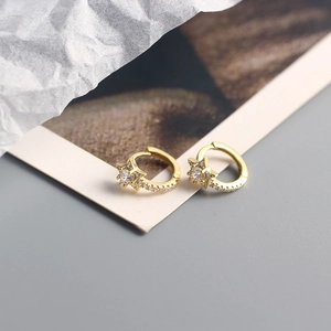 Detailed view of gold star-shaped earrings with cubic zirconia on white crumpled paper