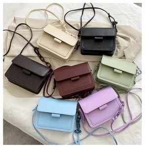 Flat lay of small crossbody bags in seven colors with chain detail and matte finish