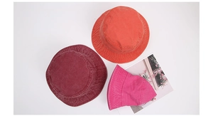 Detailed overhead shot of vintage washed cotton bucket hats in wine red and orange colors