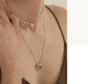 Close-up of layered 925 sterling silver beaded choker and U-shaped pendant necklace
