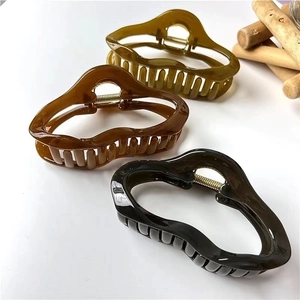 Elegant irregular hair claw clips in three colors displayed on a minimalist wooden prop