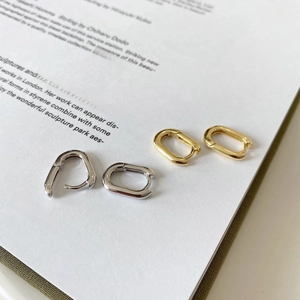 Detail of minimalist geometric oval hoop earrings in polished gold and silver finishes