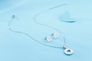 Detailed view of silver heart pendant and earring set on a light blue decorative background