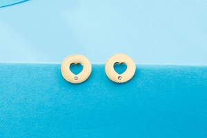 Detailed macro view of golden heart cutout earrings with small sparkling diamond accents