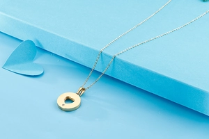 Detail showing gold heart pendant with crystal on blue background with matching earrings