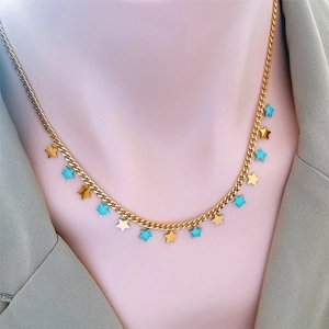 Elegant gold titanium steel necklace with blue star moon pendants on a model with green blazer