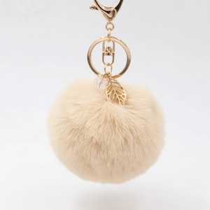 Portachiavi con pompon in peluche beige con ciondolo a foglia dorata e perla su bianco