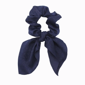 Detailed view of deep blue satin scrunchie with long ribbons and smooth texture
