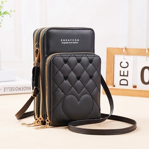 Detailed side view of black quilted heart crossbody bag with three zipper compartments