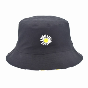 Detail of embroidered white daisy pattern on a black cotton bucket hat with yellow center