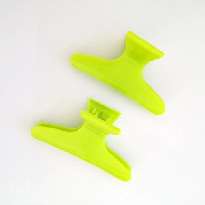 Due fermagli per capelli professionali in plastica verde neon da 8 cm su sfondo bianco