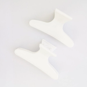 Dettaglio di due fermagli per capelli in plastica bianca a onde per lo styling