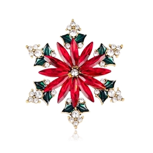 Close-up of snowflake brooch with red teardrop crystals and green enamel leaves