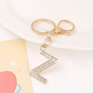 Detailed view of gold letter Z keychain with white rhinestones on a white ceramic plate