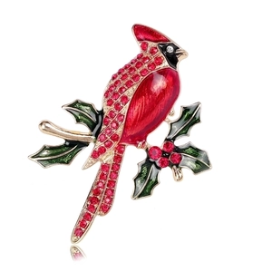 Close-up of a cardinal bird brooch with red enamel and crystals on a holly branch