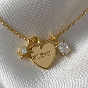 Gold Mom necklace with zircon star and heart charms on elegant white silk background