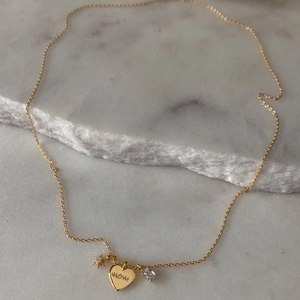 Gold Mom necklace with heart pendant, star charms and crystals on marble background