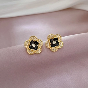 Macro detail of camellia flower stud earrings with white zircons and black enamel inlay